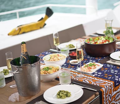 Dining table aboard a yacht prepared with food, wine and dishes for guests during a Java Yachting charter.