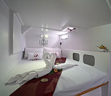 Luxury yacht charter cabin with double berth, fresh white linen and decorative towel arrangement aboard a Java Yachting charter vessel.