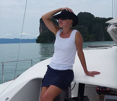Guest relaxing on deck aboard a sailing yacht surrounded by tropical islands during a Java Yachting charter in Thailand.