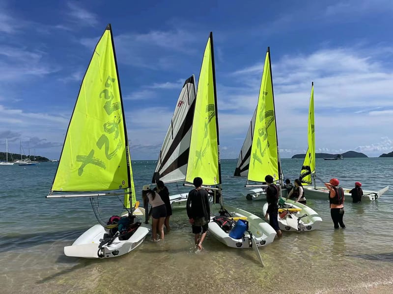 Students preparing RS Zest sailing dinghies in shallow tropical water during a Java Yachting dinghy sailing course in Phuket, Thailand.