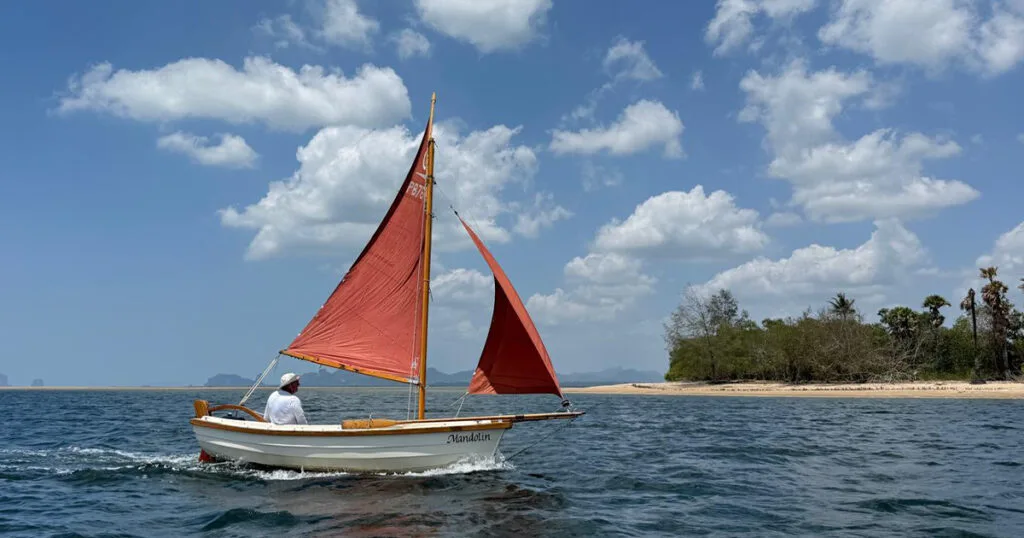 Mandolin traditional Post Boat sailing past a tropical island in Krabi, Thailand