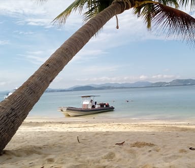 Motorboat anchored off a tropical beach during a Java Yachting boating experience in Thailand