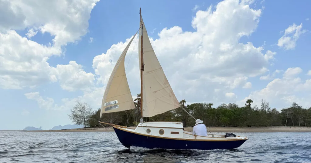 Stornaway 18 traditional sailing boat passing a tropical shoreline in Krabi, Thailand